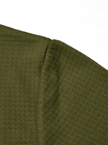 Macro shot of olive green waffle knit fabric showing premium texture and shoulder seam detail