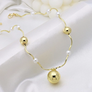 Close-up of golden wavy chain necklace with white pearls and metal beads on white silk