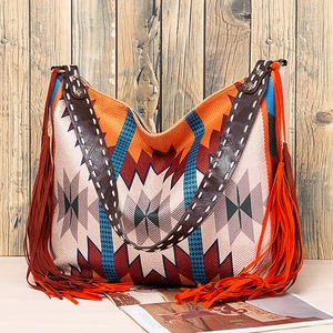 Detail of bohemian woven tote bag featuring geometric patterns and long side fringes