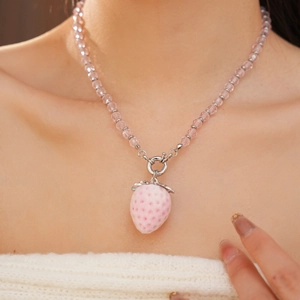 Detailed view of pink strawberry pendant necklace with transparent beads on a model