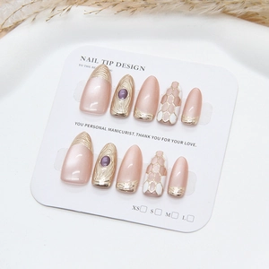 Handmade champagne pink press-on nails with golden lattice and purple gemstone accents