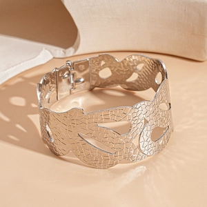 Detailed close-up of wide silver metal bracelet with scale texture and hollow-out design