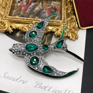 Vue détaillée d'une broche hirondelle émeraude avec cristaux et émail vert élégant