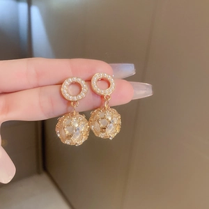 Macro detail of gold-plated hoop earrings with intricate mesh and pearl embellishments