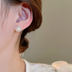Detail of silver hollow flower stud earrings worn by a model in soft lighting