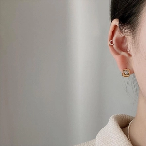 Detailed view of gold rectangle earrings with heart zircon and a moon-shaped ear cuff