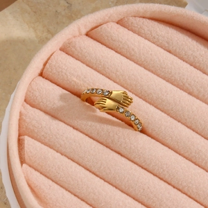 Macro shot of gold-plated hugging hands ring with zircon stones in a pink velvet box