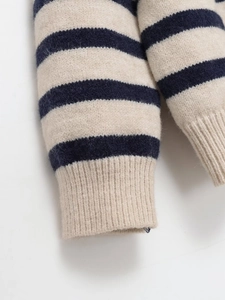 Detail of ribbed cuffs on striped knit sweater featuring navy and cream horizontal patterns