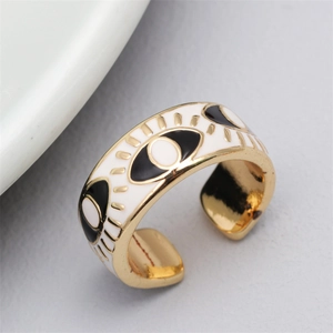 Macro detail of golden evil eye open ring featuring black and white enamel finish