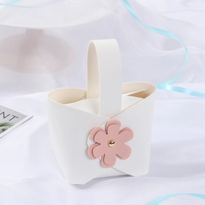Close-up of elegant white wedding favor box with pink floral ornament and gold stud