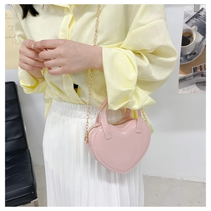 Close-up of a pink heart-shaped jelly bag with a gold chain strap on a model