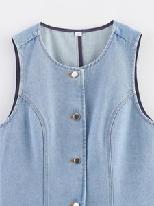 Detail shot of light blue denim vest with buttoned crew neck and clear fabric texture