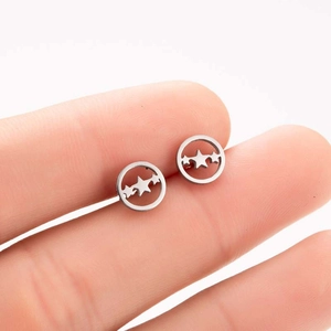 Detail shot of hollow double star stud earrings in silver held to show actual size