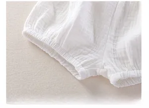 Detail of baby white muslin shorts showing elastic leg cuffs and breathable cotton texture