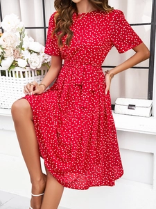 Robe longue chic à pois rouges avec manches courtes et ceinture dans un cadre lumineux