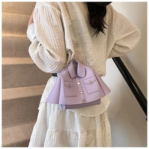 Detail of creative purple jacket-shaped crossbody bag with metal chain strap worn by model