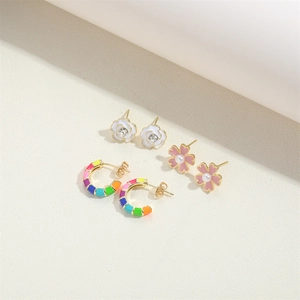 Three pairs of elegant gold-tone earrings featuring floral motifs and rainbow C-hoops