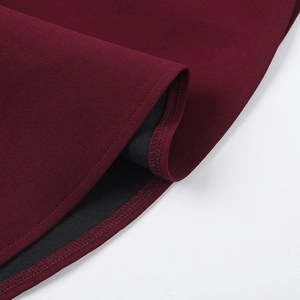 Detailed close-up of wine red fabric texture and double-stitched hem on the dress