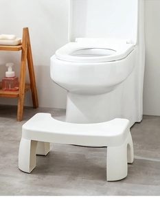 U-shaped ergonomic white plastic toilet footstool placed in a modern bathroom setting