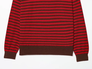 Détail d'un pull rayé rouge et marron montrant les finitions côtelées aux poignets