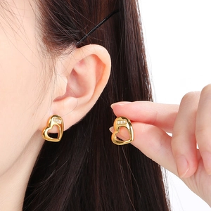 Macro shot of gold hollow heart earrings with small inlaid diamonds on a model