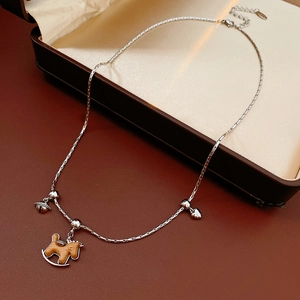 Gros plan du collier argenté avec cheval à bascule en bois, cœur et petits pendentifs
