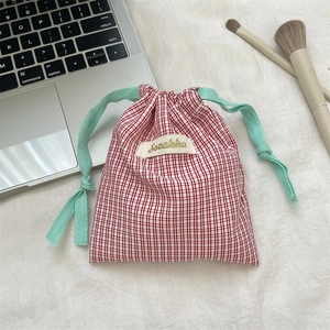 Close-up of red and white checkered drawstring pouch with mint green cotton ribbons