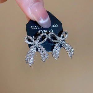 Macro shot of silver bow earrings with sparkling zircon tassels and SILVER 1000 mark