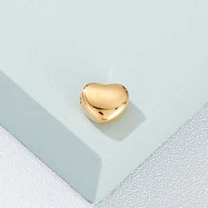 Polished heart-shaped gold pendant on minimalist display for jewelry making projects