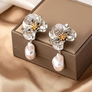 Artistic flower earrings with baroque pearl drops displayed on a brown leather jewelry box