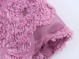 Macro shot of purple textured fabric with 3D floral fringe detail on mesh material