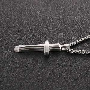 Vue macro d'un pendentif croix en métal brossé argenté avec sa chaîne assortie