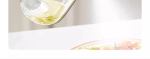 Macro shot of glass oil sprayer nozzle releasing a fine mist over a food plate