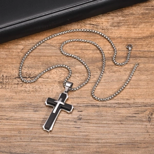 Vue détaillée du pendentif croix double épaisseur avec chaîne en acier sur bois