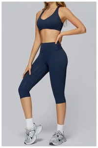 Detail of high-waist navy yoga leggings and matching sports bra on fitness model