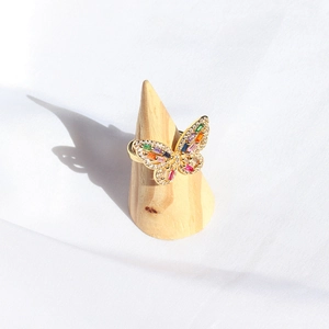 Macro shot of gold butterfly ring with colorful cubic zirconia casting a shadow