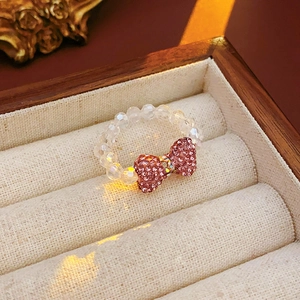 Close-up of pink crystal bow ring on a velvet jewelry box with warm lighting