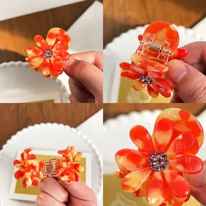 Pince à cheveux fleurie en acétate avec texture marbrée orange et strass étincelants