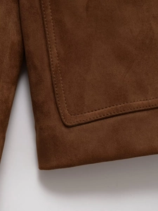 Close-up of double-row stitching and suede texture on brown leather jacket hem