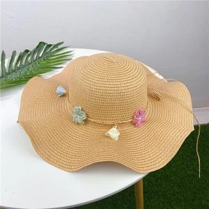 Detailed macro of woven straw hat with colorful textile flowers and fringe tassels