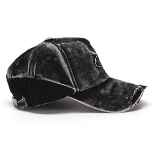 Detail showing distressed denim baseball cap with frayed holes and red stitching