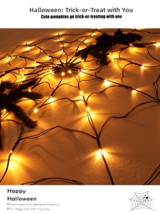 Detail of warm yellow LED spider web lights with two plush black spiders for Halloween