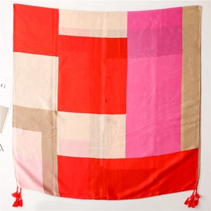 Detail view of large square scarf with bold geometric blocks and red tassels on corners