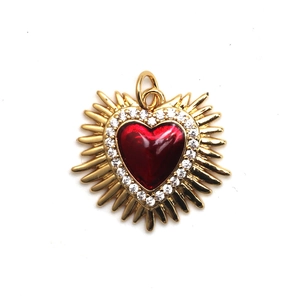 Detailed view of a golden sacred heart pendant with red enamel and sparkling zircon stones