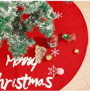 Detail of red knitted Christmas tree skirt with Merry Christmas embroidery and snowflakes