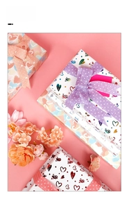 Detail of heart pattern gift wrapping paper with laser foil and polka dot ribbon