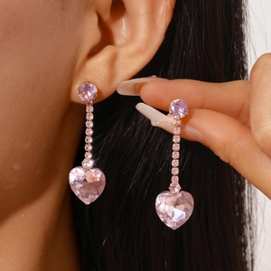 Close-up of pink heart-shaped crystal fringe earrings with zircon tassel on a model