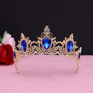 Detail of baroque vintage golden crown with large blue teardrop gems and white crystals