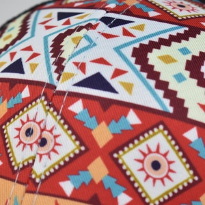 Macro detail of geometric bohemian print fabric and white stitching on baseball cap