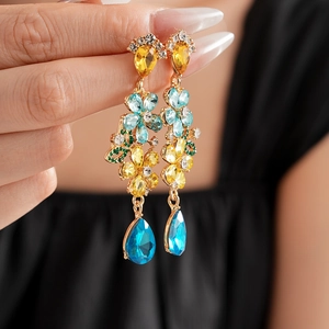 Detail of vintage style gold flower earrings with colorful rhinestones and blue tassels